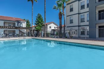 A swimming pool surrounded by palm trees and apartment buildings.